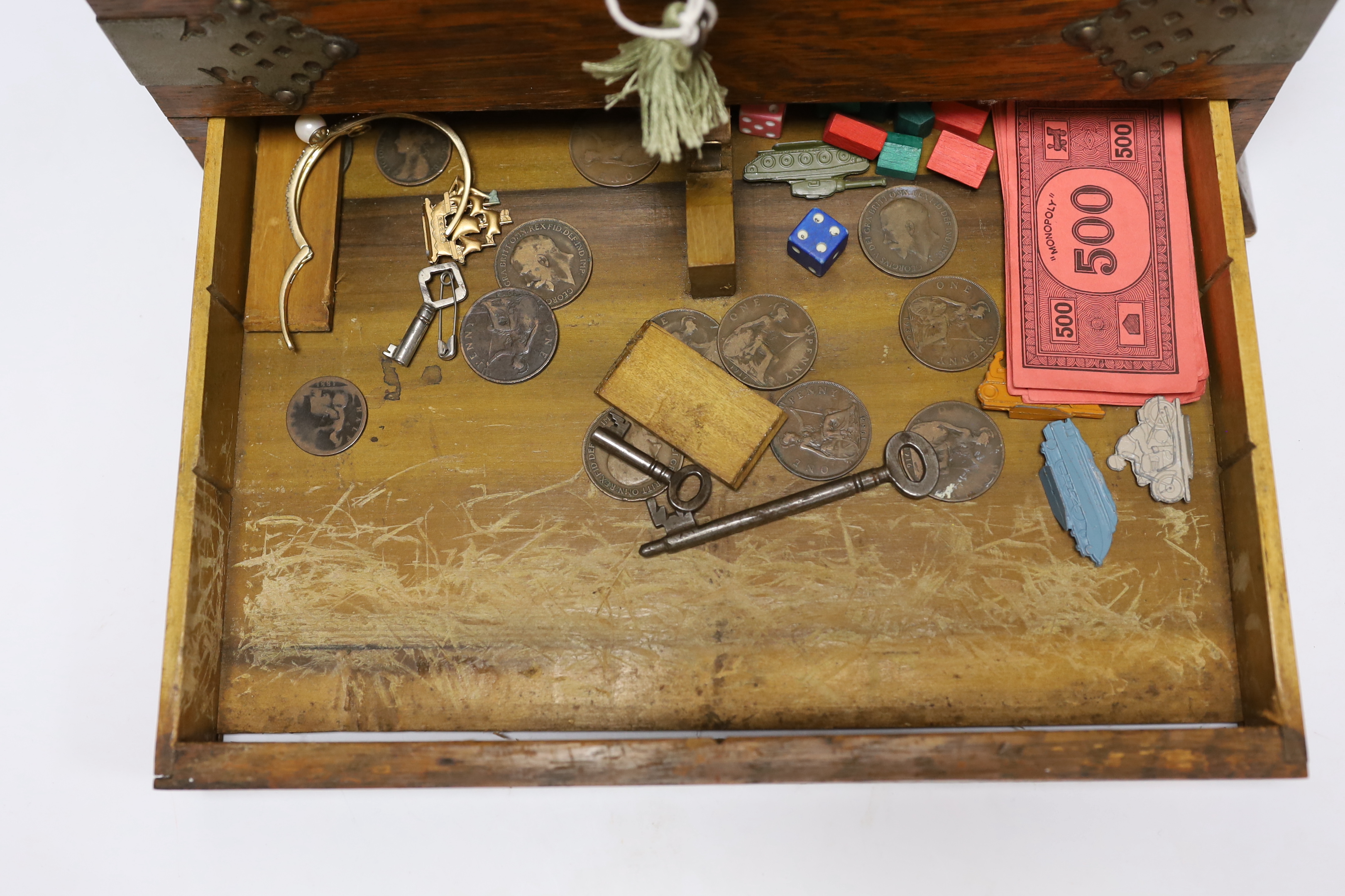 An oak tantalus/compendium containing three cut glass decanters, chess and draught sets, etc.